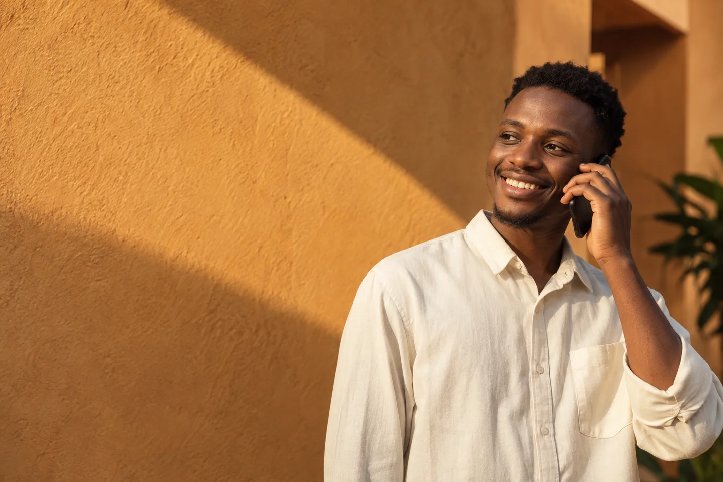 Umusore avugira kuri telefoni hafi y’urukuta rw’umuhondo.